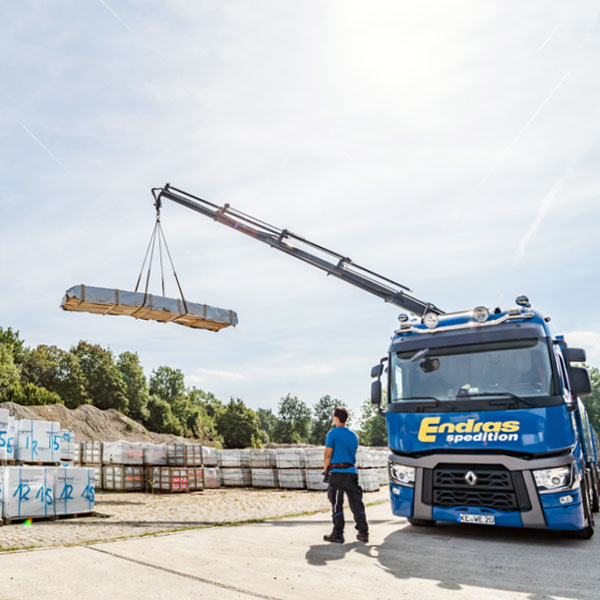 Ein Ladekran hebt eine verpackte Ladung von einem Endras-Lkw