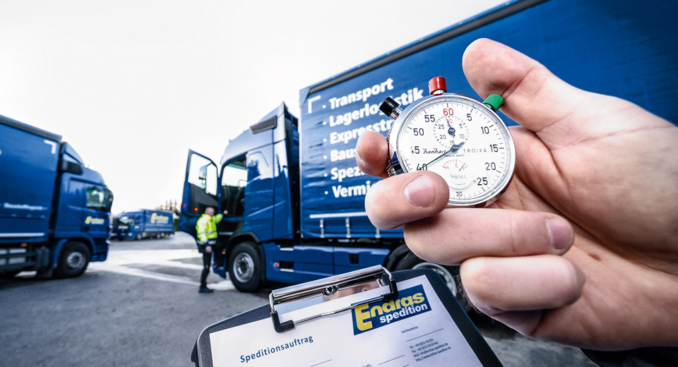 Stoppuhr vor einem LKW mit Leistungsaufdruck auf der Plane