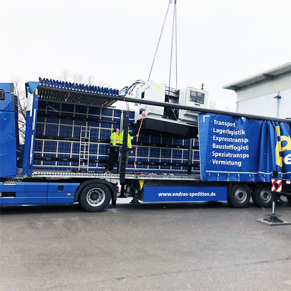 Ein Kran lädt eine Industriemaschine auf einen Endras-Sattelauflieger