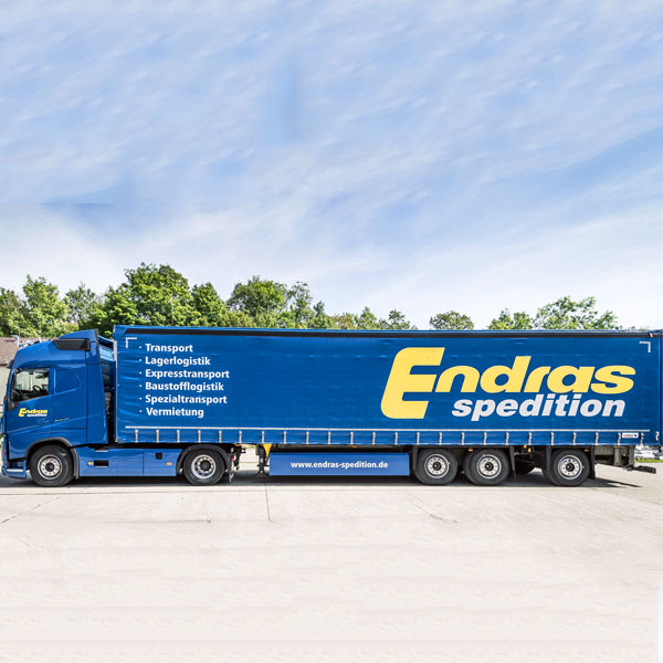 Ein Endras-Lkw mit Plane und Leistungsangebot, seitlich fotografiert vor Bäumen